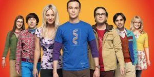 Les sept personnages de la série The Big Bang Theory alignés sur fond orange, univers geek par excellence
