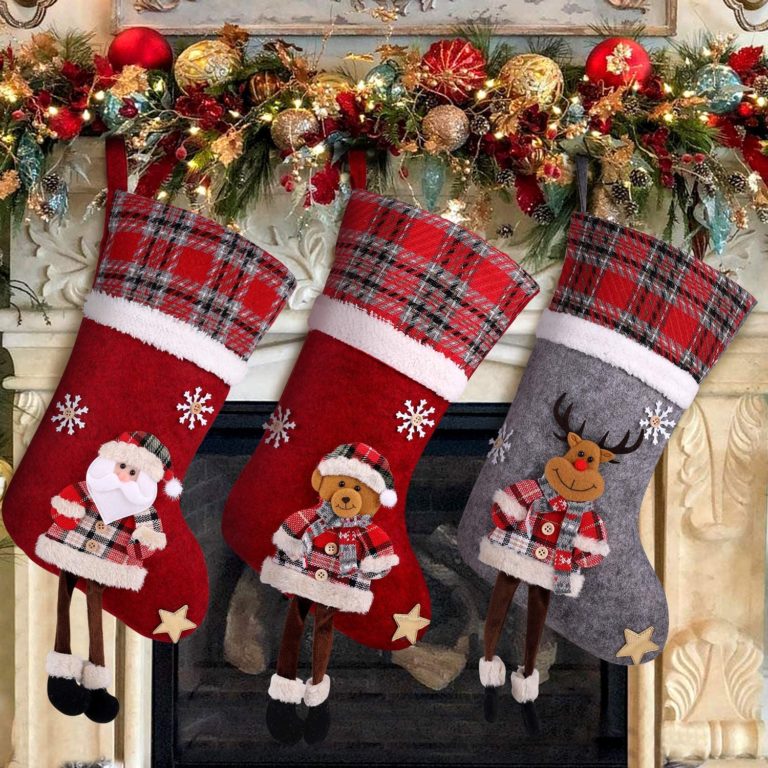Trois chaussettes de Noël à revers tartan suspendues à la cheminée, décorées d'un père Noël, d'un ours et d'un renne