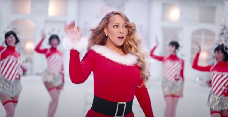 Mariah Carey en tenue de mère Noël rouge et blanche entourée de danseurs dans son clip de chanson de Noël