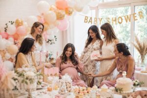 Baby shower entre amies : future maman entourée de ses invitées sous une arche de ballons roses et dorés