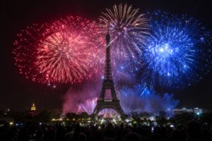 Feu d'artifice du 14 Juillet illuminant la tour Eiffel de bleu, blanc et rouge au-dessus de la foule