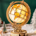 Maquette en bois d'un globe terrestre lumineux monté sur engrenages, posée dans un décor enneigé