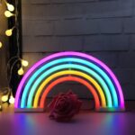 Néon LED en forme d'arc-en-ciel multicolore allumé contre un mur de briques blanches