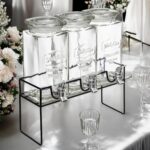 Bar à cocktails : trois bonbonnes en verre à robinet sur support métallique noir et verres à pied