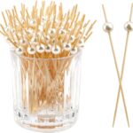 Pics à brochettes en bois surmontés d'une perle nacrée, rangés dans un verre pour un buffet chic