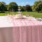 Chemin de table en tulle rose perlé sur une table de gâteau dressée en extérieur