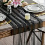 Chemin de table en tulle noir pailleté d'or sur une table en bois, décor de mariage contrasté