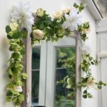 Guirlande de fleurs artificielles blanches et eucalyptus habillant un miroir ancien, décor champêtre