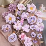 Têtes de fleurs artificielles lilas et parme disposées sur un miroir doré, décor de mariage mauve
