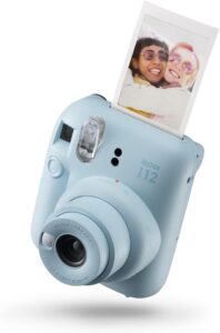 Appareil photo instantané bleu ciel qui imprime une photo souvenir de deux amies, pour garder la trace de la fête