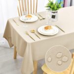 Nappe beige unie dressée avec assiettes blanches et couverts dorés, zoom sur le tissu déperlant anti-taches