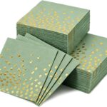 Piles de serviettes en papier vert sauge parsemées de pois dorés pour une table de baptême chic