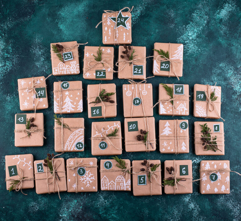 Calendrier de l'Avent maison en sapin : 24 paquets en kraft numérotés, ficelle et brins de verdure sur fond vert