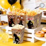 Boîtes à pop-corn imprimées silhouettes de détective garnies de chips et friandises sur un buffet de murder party