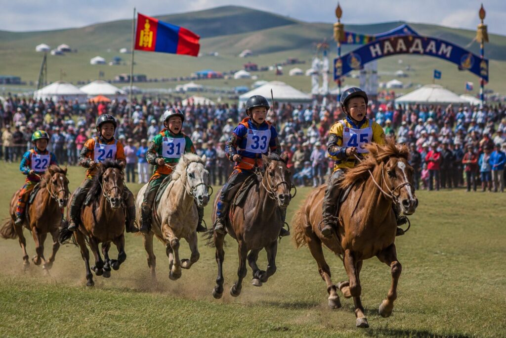 Jeunes cavaliers numérotés lancés au galop dans la steppe pendant la course de chevaux du Naadam en Mongolie