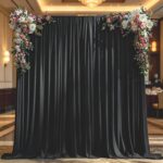Rideau noir en voilage tendu sur un portique et orné de fleurs, fond sombre pour un coin d'entrée ou un photobooth magique