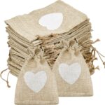 Sachets en toile de jute ornés d'un cœur blanc et fermés par une cordelette, pour offrir les dragées d'un baptême nature