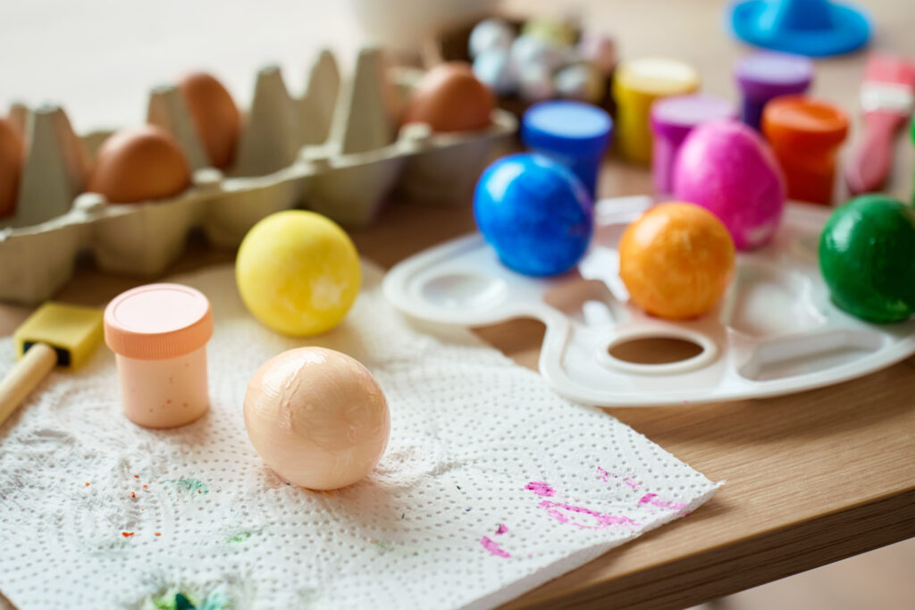 Œufs peints de couleurs vives, boîte à œufs et palette de peinture sur une table pour un calendrier de l'Avent récup'